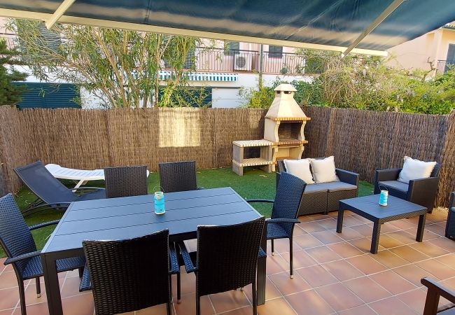 Garden with armchairs, barbecue, table, awnings and sun loungers